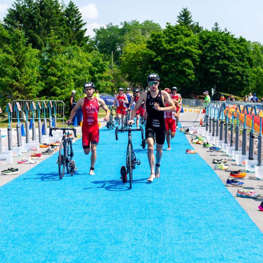 Athlètes qui courent avec leur vélo dans une zone de transition